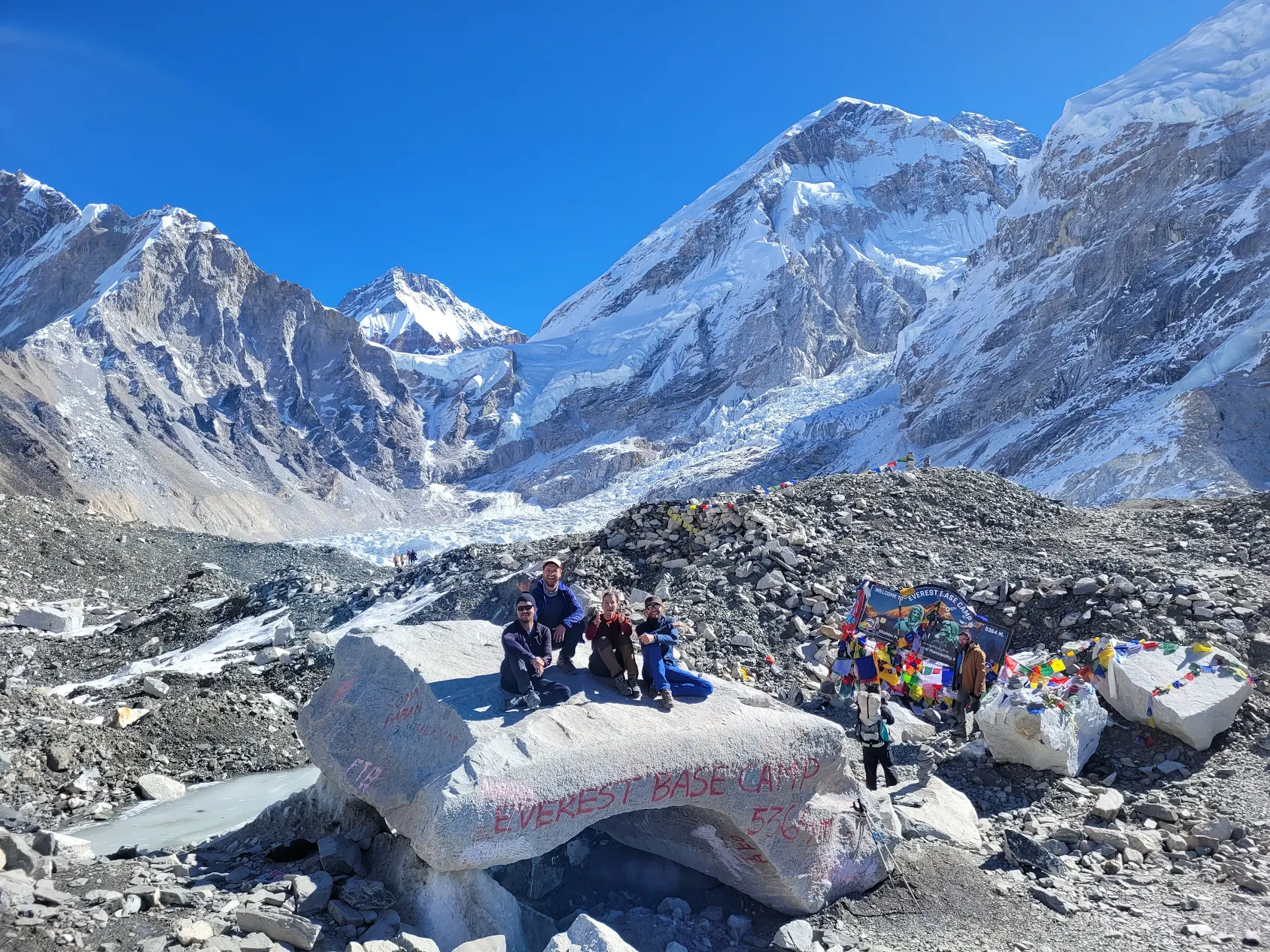Elysian Quest Team seating on the iconic stone at Everest Base Camp